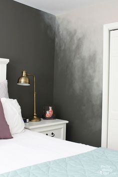 a white bed sitting in a bedroom next to a wall painted black and white with gold accents