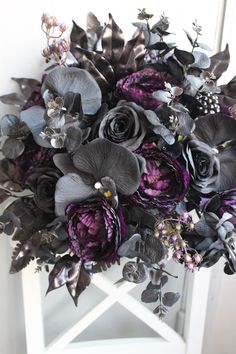 a bouquet of purple and black flowers on a white stand