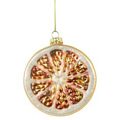 a glass ornament hanging from a gold chain on a white background with an orange slice cut in half