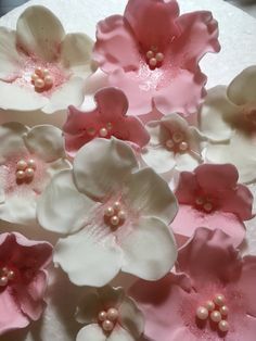 pink and white flowers on top of a cake with pearls in the middle for decoration