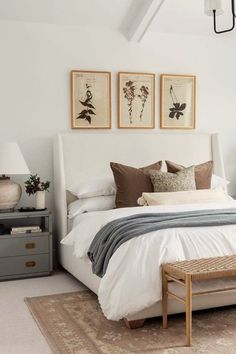 a white bed sitting in a bedroom next to two lamps and pictures on the wall