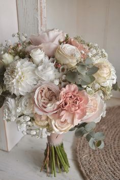 a bouquet of flowers sitting on top of a wooden table next to a white door