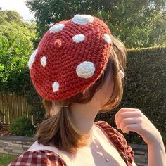 a woman wearing a red and white knitted hat with polka dots on the top