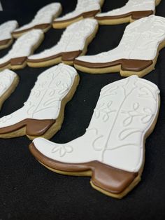 cookies decorated with cowboy boots are displayed on a black tablecloth for display or to be eaten