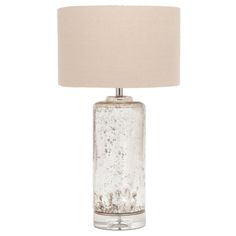 a glass table lamp with a beige shade on the base and a white linen lampshade