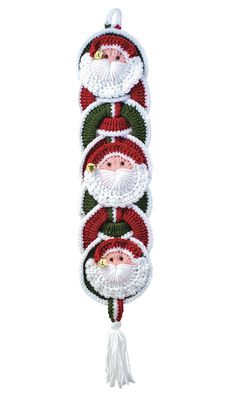 three santa claus ornaments hanging on a white wall with red and green trimmings