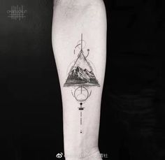 a man's arm with a mountain and compass tattoo on the left inner forearm