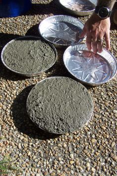 three metal plates sitting on top of a gravel covered ground