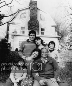 a black and white photo of a family in front of a house