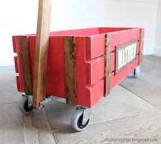 a red wagon sitting on top of a floor next to a wooden stick in it