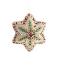 an ornament hanging from a string on a white background, decorated with leaves and beads