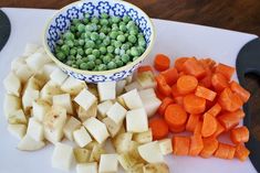 there are carrots, potatoes and peas on the cutting board