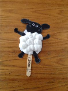 a black and white sheep on a wooden stick