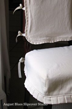 a white chair with ruffled edges and a pillow on it's backrest