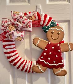 a christmas wreath with a gingerbread man hanging from it's side on a door