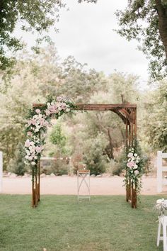 an outdoor ceremony setup with white chairs and pink flowers on the arbors at this wedding