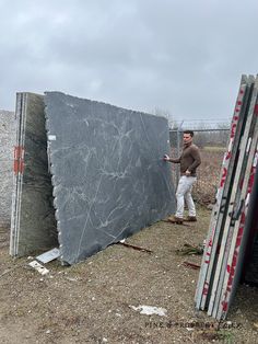 a man standing next to a large slab of granite