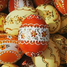 an orange and white decorated egg surrounded by other yellow and red colored eggs with designs on them