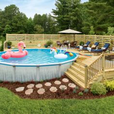 an above ground pool surrounded by decking and lawn furniture with flamingos floating in the water