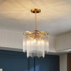 a chandelier hanging from the ceiling in a room with blue walls and gold trim