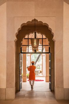 a woman in an orange dress is walking down the hall