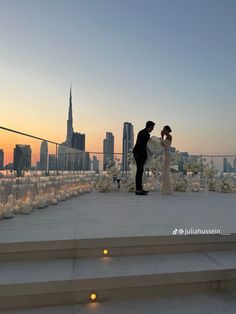 a bride and groom standing on the roof of a building in front of a cityscape