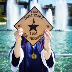 a woman holding up a graduation cap with the words i am imprinted on it