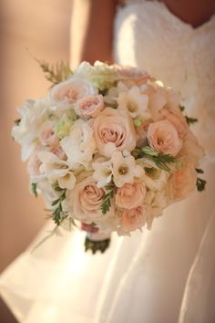 a bride holding a bouquet of white and pink flowers