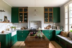 a kitchen with green cabinetry and wooden flooring, along with white counter tops