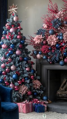 two christmas trees with ornaments on them in front of a fireplace and blue velvet chair