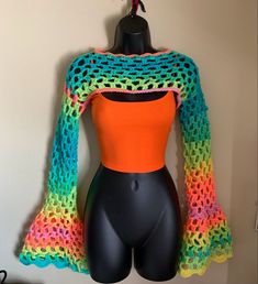 a mannequin wearing an orange top and colorful crochet shawl