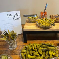 pickles are arranged in glass bowls on a wooden table next to a sign that says pickle bar