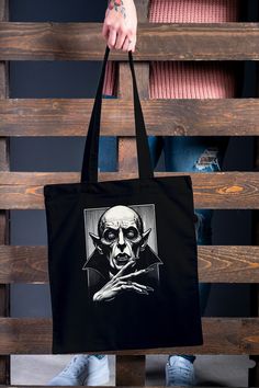 Immerse yourself in the dark world of Nosferatu with this fascinating Occult Vampire Tote Bag! The unique design features the iconic face of the Nosferatu Vampire in a minimalist yet impressive style on high-quality fabric. This spacious tote bag not only offers space for your shopping, but is also a real eye-catcher for your everyday style or special occasions. These long handle tote bags meet all your tote bag needs and are environmentally conscious at the same time. These totes feature reinfo Vampire Nosferatu, Nosferatu Vampire, Gothic Bag, Dark World, Halloween Tote Bag, Halloween Tote, The Dark World, Vintage Horror, Environmentally Conscious