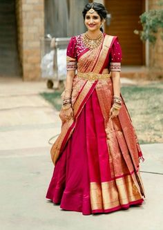 a woman in a pink and gold sari is walking down the street with her hand on her hip