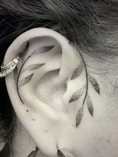 a woman's ear with black leaves on it