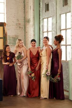 a group of women standing next to each other wearing dresses and holding bouquets in their hands