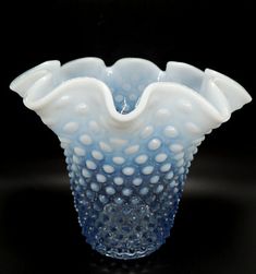 a blue and white glass vase sitting on top of a table next to a black background