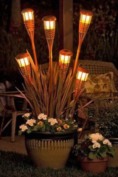 an arrangement of lights in a potted planter with white flowers on the ground