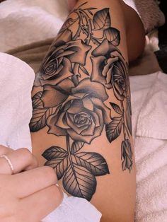 a woman's arm with black roses and leaves tattoo on the left side of her body