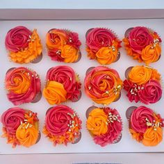 cupcakes decorated with orange and pink flowers in a box