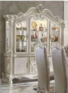 a dining room table and chairs in front of a white china cabinet with glass doors