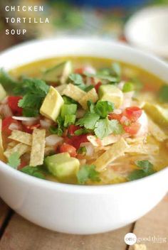 a bowl of chicken tortilla soup with avocado and cilantro