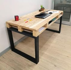 a desk made out of pallet wood with a laptop on it and a plant in the corner