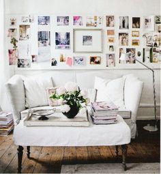 a living room filled with white furniture and pictures on the wall above it's coffee table