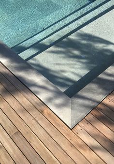 an empty swimming pool in the middle of a wooden decking area next to a tree