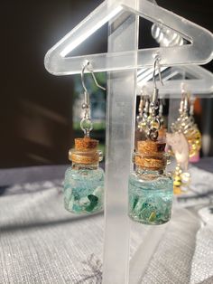 two glass bottles with corks are hanging from a hook - on earring holder