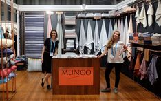 two women standing in front of a store display with shirts hanging on the walls and behind them