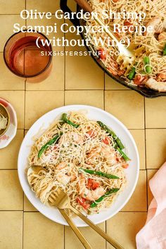 a white plate topped with pasta next to a pan of shrimp and veggies