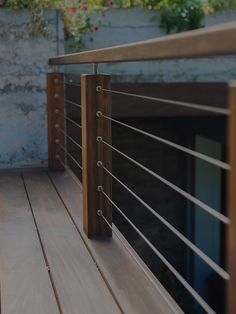 a wooden deck with metal railings next to a wall and potted planter