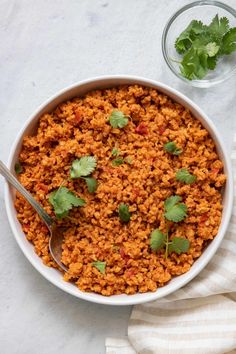 a bowl filled with rice and cilantro on top of a white table cloth